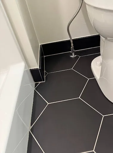 Spotless commercial restroom with black hexagonal floor tile, clean white grout, and a gleaming toilet